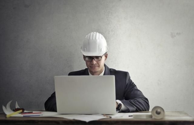 Man in a hardhat working on a laptop